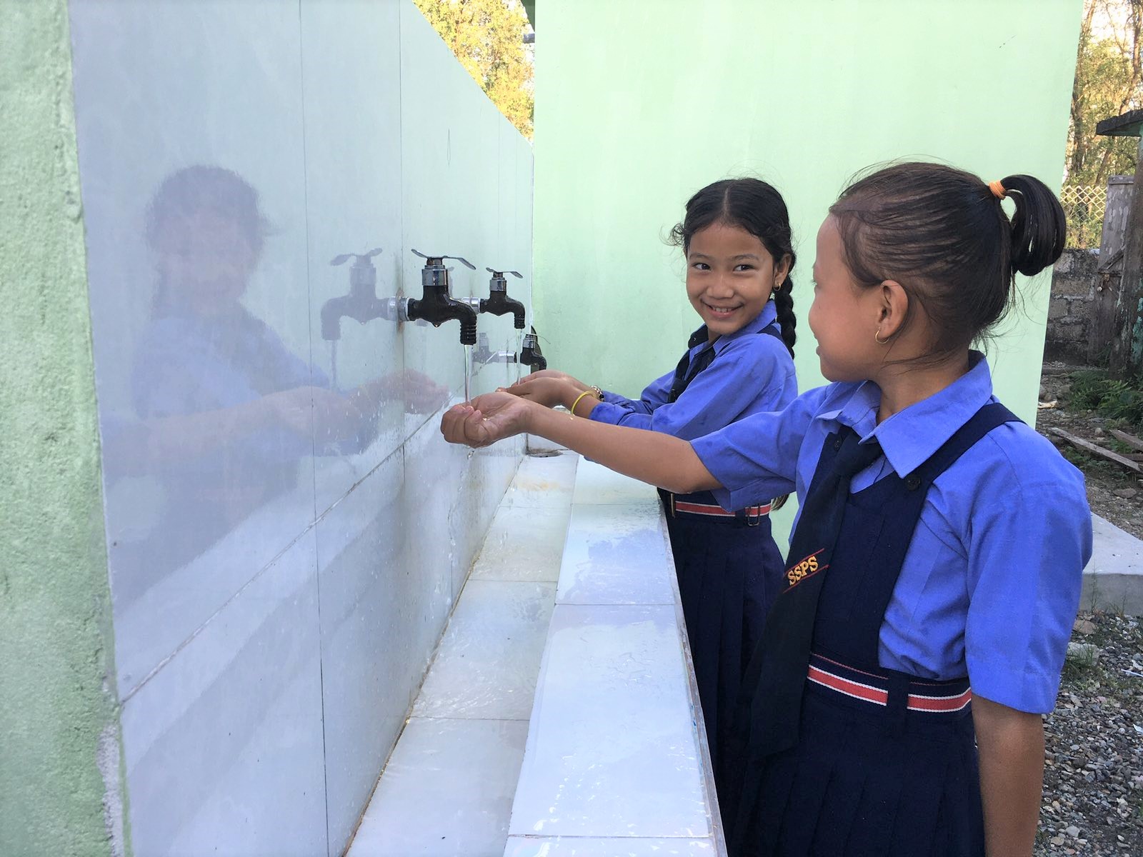 Zwei Mädchen stehen an einem Waschbecken und waschen sich die Hände unter fließendem Wasser